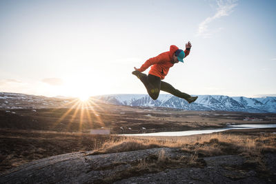 Man jumping with mountains and sun in background