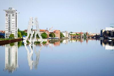 Molecule men statue on spree river against clear sky