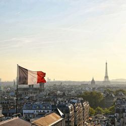 French flag against eiffel tower in city during sunset