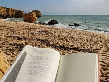 Open book on beach against sky