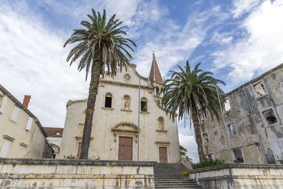 Low angle view of palm trees in front of the church against sky