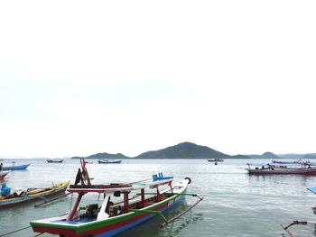 Boats moored in sea against clear sky