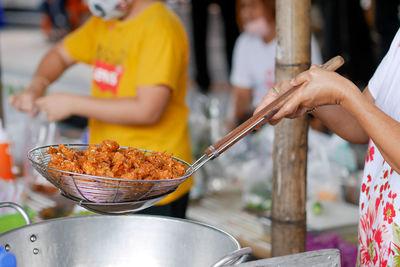 Midsection of woman holding meat on barbecue grill