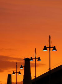 Low angle view of silhouette bridge against orange sky