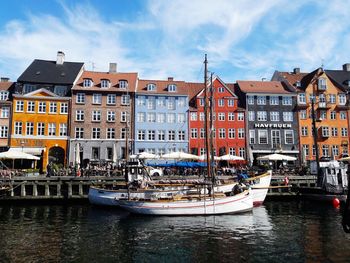 Boats moored in canal by buildings in city