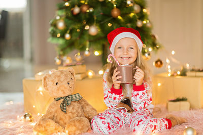 Portrait of smiling young woman holding christmas tree