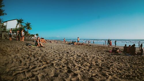 People on beach against clear blue sky