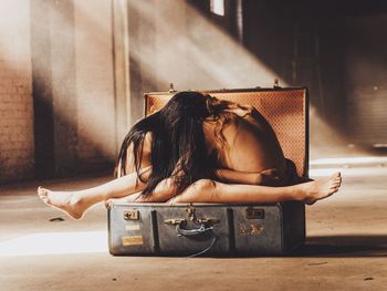 Naked women sitting while embracing in suitcase