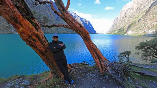 Man standing in sea against mountain