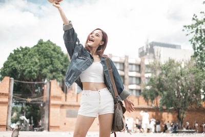 Full length of young woman standing against sky