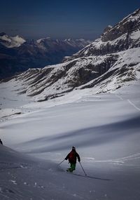 Man skiing on snowcapped mountain against sky