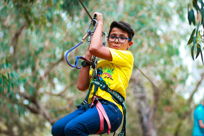 Portrait of teenage boy zip lining at forest