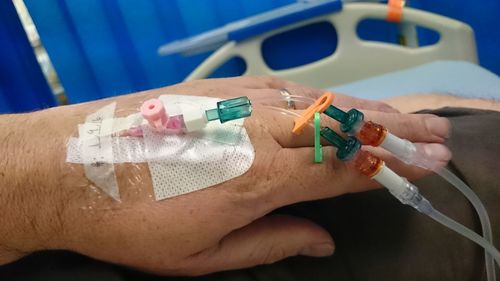 Cropped hand of man with iv drip in hospital