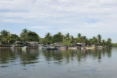 Boats in calm sea against cloudy sky