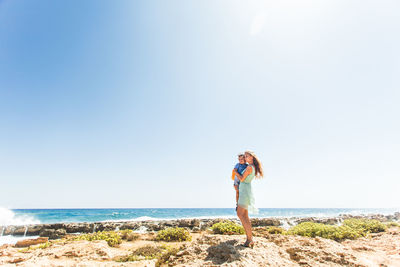 Full length of woman standing at beach against sky