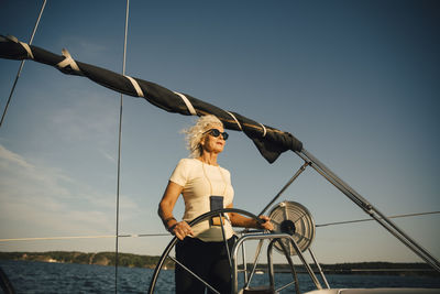 Woman by sailboat against sea against clear sky