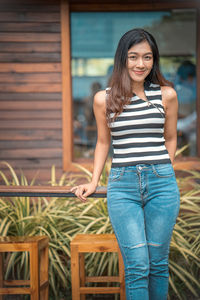 Portrait of young woman standing against wall