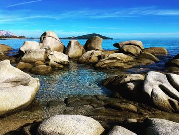 Rocks in sea against blue sky