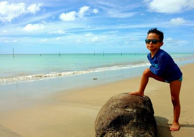 Portrait of happy boy standing on beach against sky