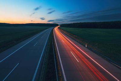 Light trails on road against sky at sunset