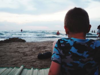 Rear view of boy looking at sea against sky