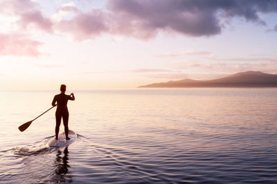 Rear view of man standing in sea against sky