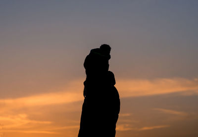 Low angle view of silhouette man against orange sky