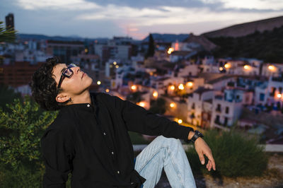 Young transgender man looking up while posing outdoors at sunset.