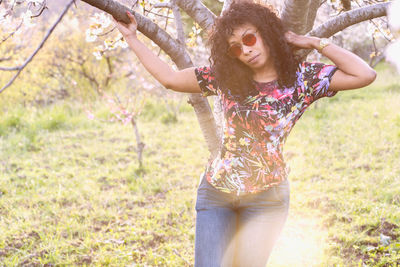 Midsection of young woman with arms raised on field
