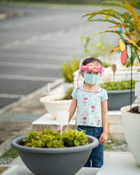 Full length of cute girl standing in flower pot