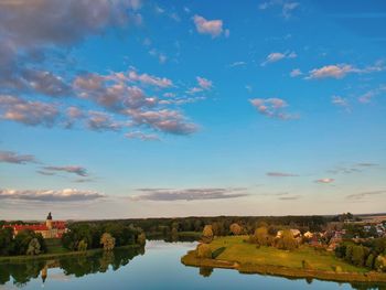 Scenic view of lake by buildings against blue sky