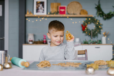 A cute little boy is sitting at the table and preparing christmas cookies. family vacation at home