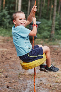 Full length of smiling boy sitting outdoors