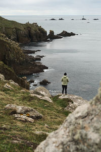 Rear view of man walking on rock by sea