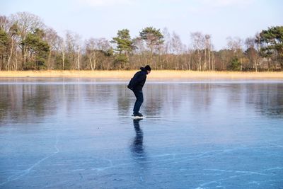 Man ice-skating on rink against trees