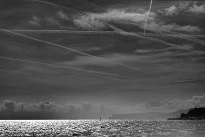 Scenic view of sea against vapor trails in sky