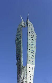 Low angle view of fish hanging against clear blue sky