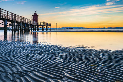 Pier over sea against sky during sunset