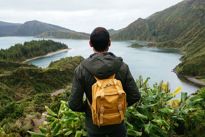 Rear view of man looking at mountains against sky