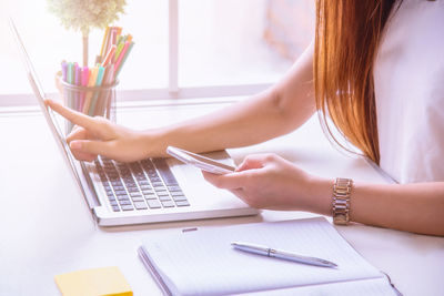 Midsection of businesswoman using laptop in office