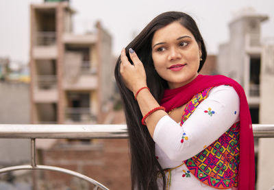 Close-up of smiling young woman looking way while standing outdoors