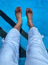 Low section of man standing by swimming pool