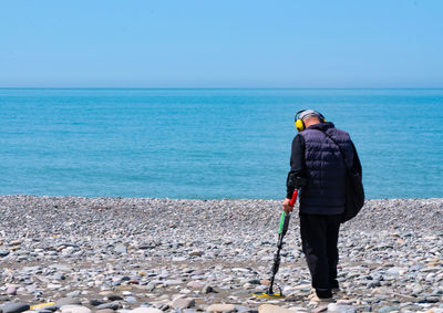 Rear view of man standing on beach against sky