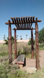 Wooden bench on field against clear sky