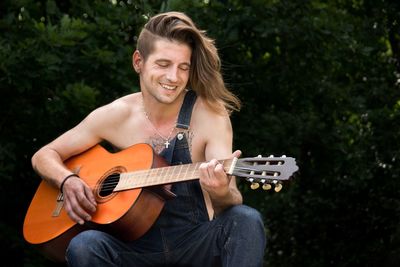 Man playing guitar against trees