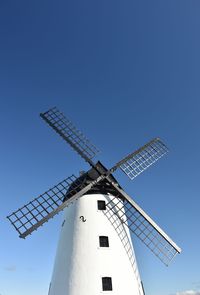 Low angle view of traditional windmill against clear blue sky