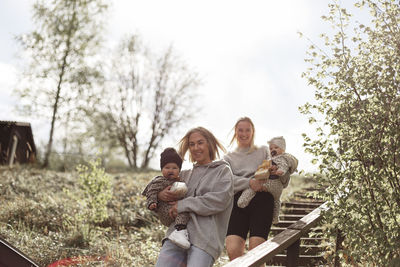 Low angle view of smiling women carrying babies