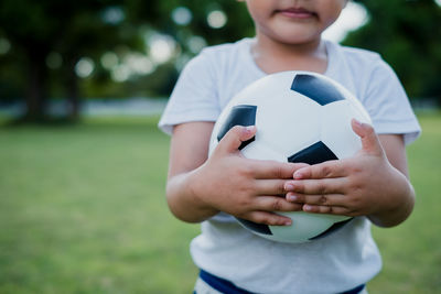 Midsection of boy holding ball on field