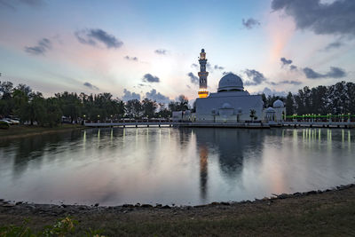 Panoramic view of lake by building against sky during sunset