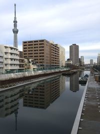 Reflection of buildings on calm river by tokyo sky tree against sky